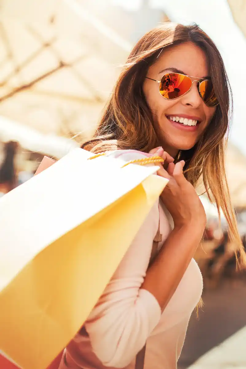 Mujer joven sonriendo con anteojos de sol y de compras